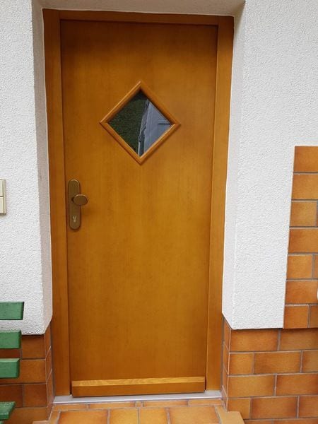 Klassische Haustür aus Holz mit kleinem rautenförmigem Glasausschnitt