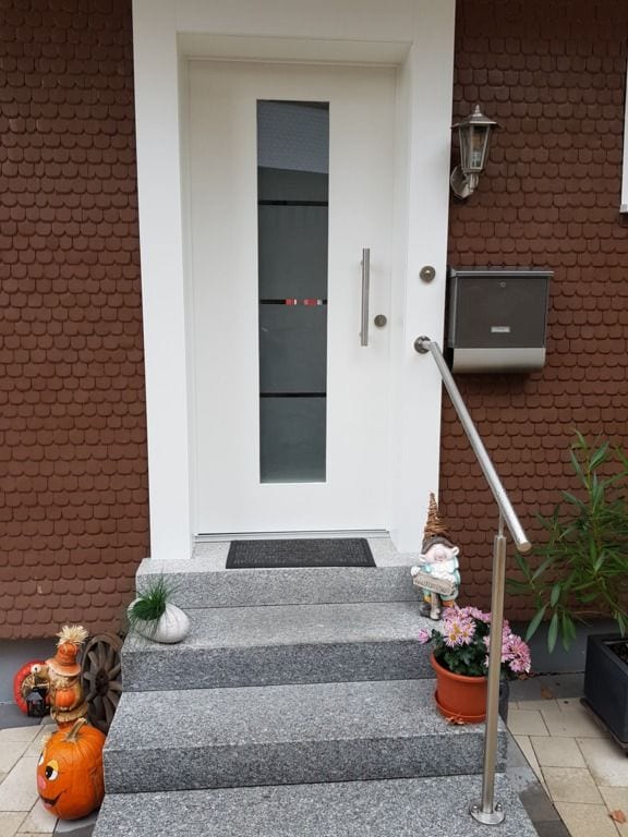 Weiße Haustür mit schmalem Glasstreifen am Ende einer Eingangstreppe