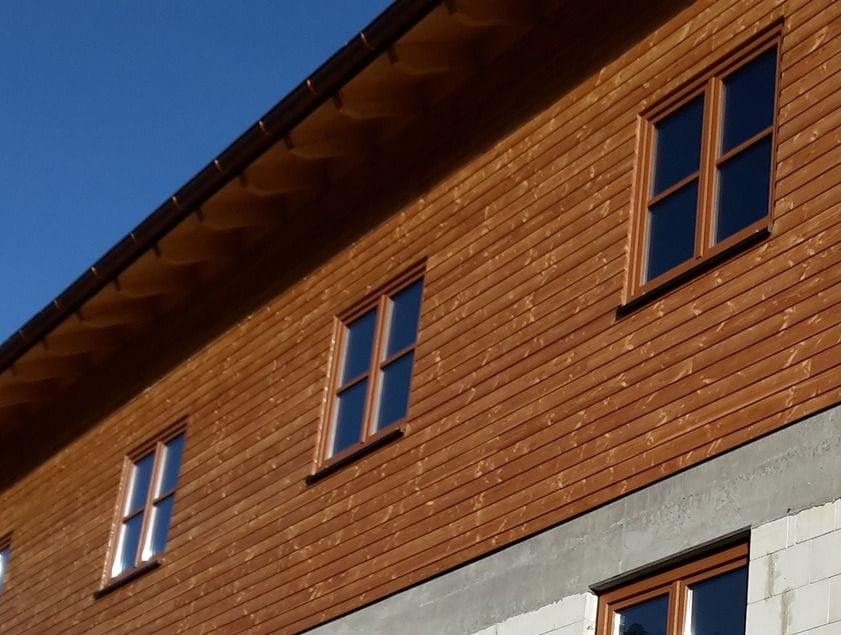 Holzfassade mit Holzfenstern vor blauem Himmel
