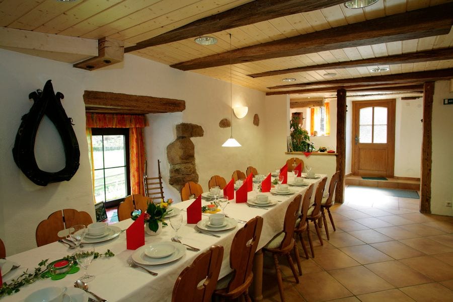 Gaststube mit Holzbalkendecke, festlich gedeckter Tafel und Holzstühlen