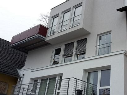 Weißes Wohn- und Geschäftshaus mit Kunststofffenstern und Jalousien