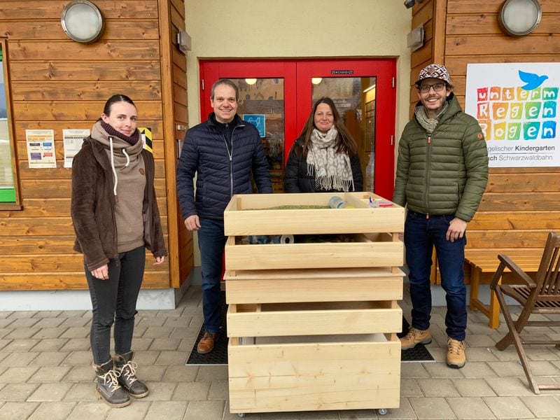 Übergabe eines Spieleweltenwagens aus Kiefernholz vor dem Kindergarten