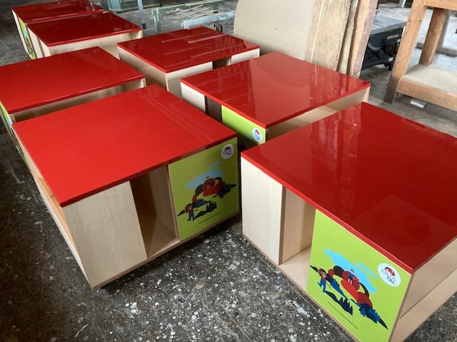 Sieben Spieltische mit roter Tischplatte und Fächern aus hellem Holz